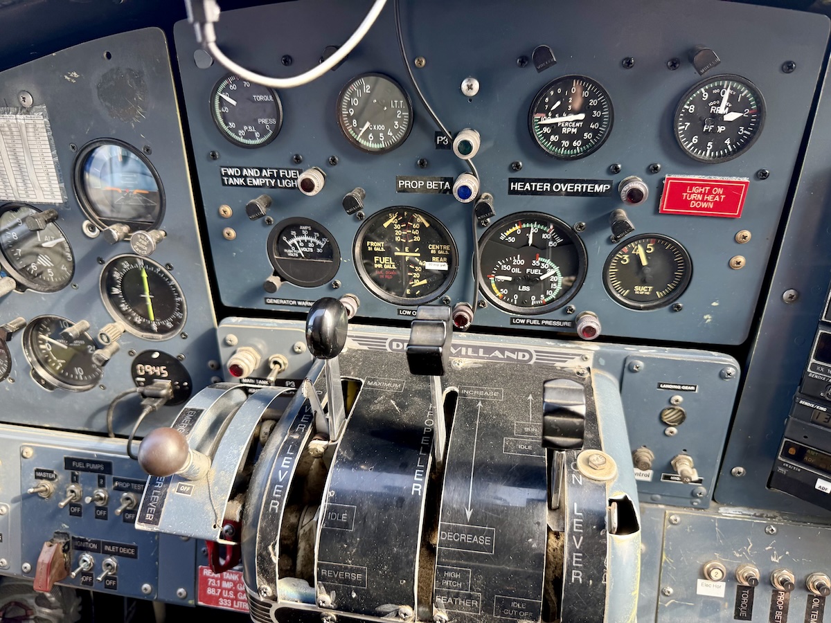 Close-up of a vintage de Havilland aircraft cockpit with various analog gauges and throttle levers.