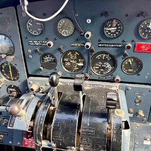 Close-up of a vintage de Havilland Beaver aircraft cockpit with various analog gauges and throttle levers.